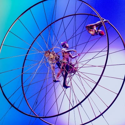 Dos artistas dentro de una gran rueda aérea.
