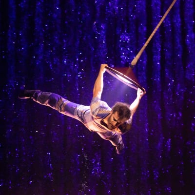 Gymnast performs an aerial act holding onto a balancing lamp in the air - Christmas Cirque du Soleil