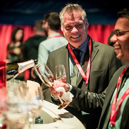 Two men are served champagne at the open bar of a Cirque du Soleil VIP area