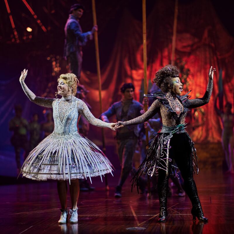 Two female dancers holding hands while waving to the crowd - Alegría