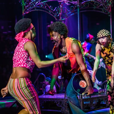 Characters dressed in colorful clothes dance on stage to the beat of the 60’s - Love Cirque du Soleil
