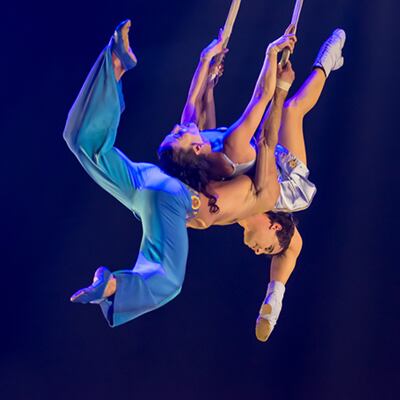 Two back to back acrobats hold on to ropes - Corteo Cirque du Soleil