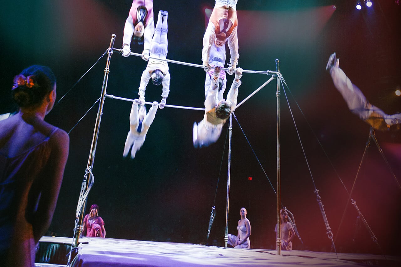 Los gimnastas se presentan en barras paralelas y algunos de ellos se paran de manos - Corteo Cirque du Soleil