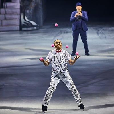 Un artiste patine sur la glace tout en jonglant avec cinq balles roses - Cirque du Soleil Crystal