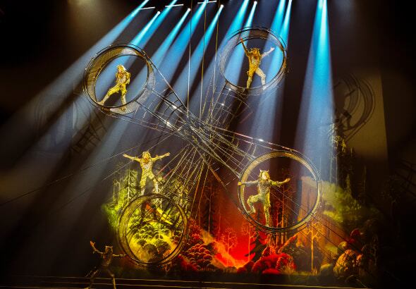 Cuatro artistas se agarran a una construcción metálica redonda que gira llamada la Rueda de la Muerte - Drawn to Life Cirque du Soleil.