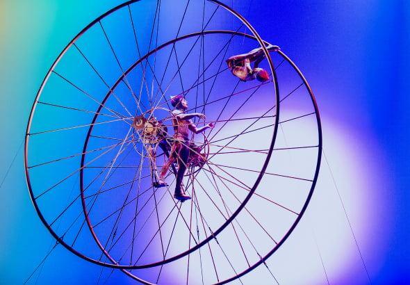 Two performers inside a large aerial wheel.