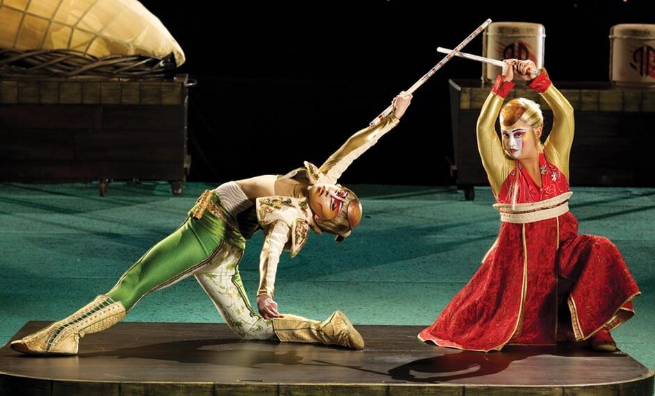 Dos artistas vestidos con ropa tradicional asiática luchan con espadas - Kà Cirque du Soleil