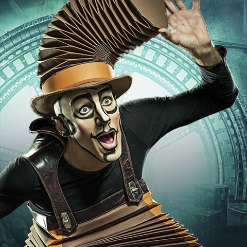 Nico is dressed in an accordion costume and  waves his hands in the air - Cirque du Soleil Kurios