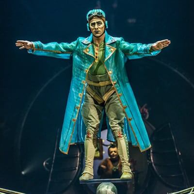 Un artiste déguisé en aviateur utilise son avion comme plate-forme pour pratiquer le Rola Bola - Cirque du Soleil Kurios