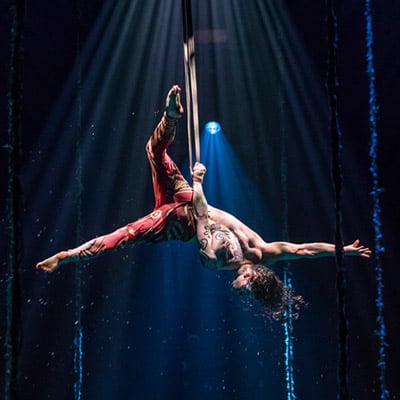 L'interprète se tient à l'envers pendant un numéro de sangles aériennes - Durée spectacle Cirque du Soleil