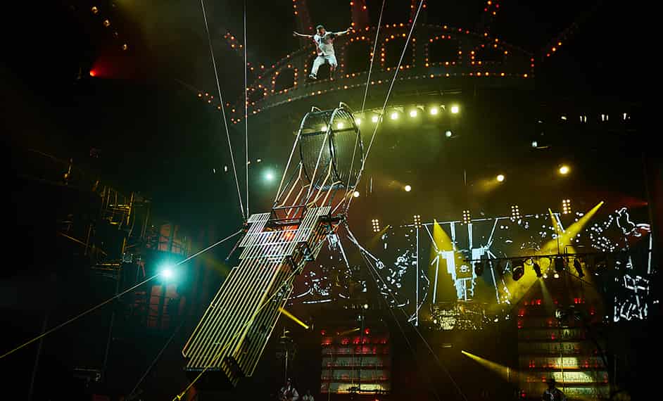 El artista salta alto sobre un artilugio que se parece al edificio empire state - Mad Apple Cirque du Soleil