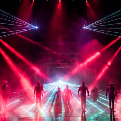 Des faisceaux lumineux rouges et blancs pointent vers les danseurs sur scène - Cirque du Soleil Michael Jackson