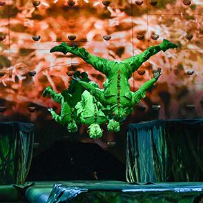 Acrobats dressed with cricket looking costumes achieve a trampoline act - Cirque du Soleil