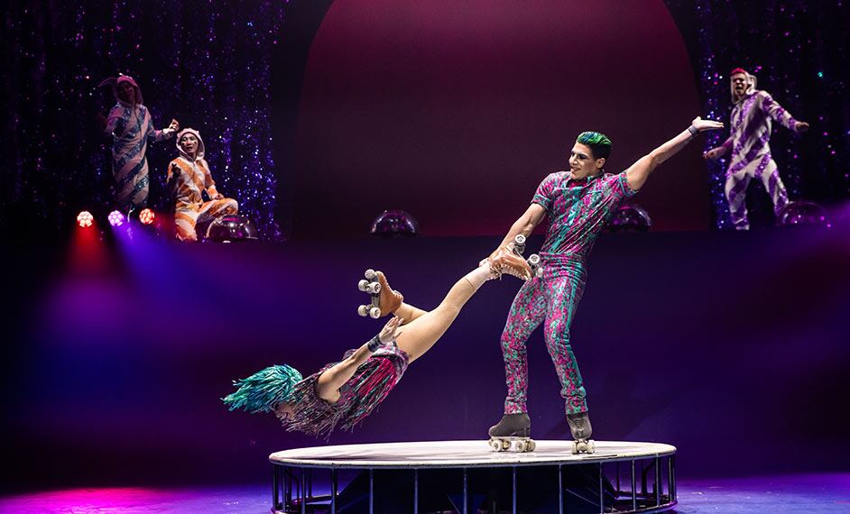 Two artists perform a roller skate duo on a small and round white platform - Twas The Night Before cirque Christmas show
