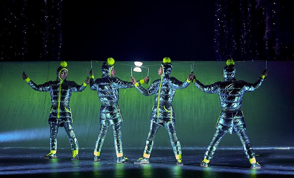 Four artists dressed in insulated light blue chrome down coats perform diabolo - cirque Twas The Night Before show