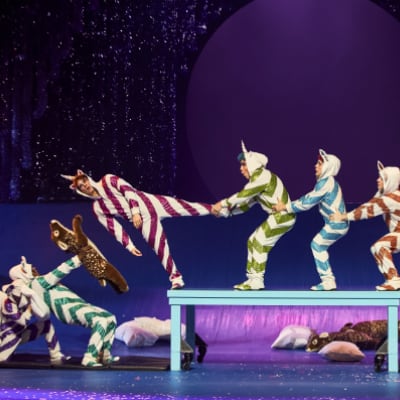 Grupo de niños en pijamas coloridos realizan acrobacias en una mesa acrobática - Twas The Night Before Cirque du Soleil espectáculo de Navidad