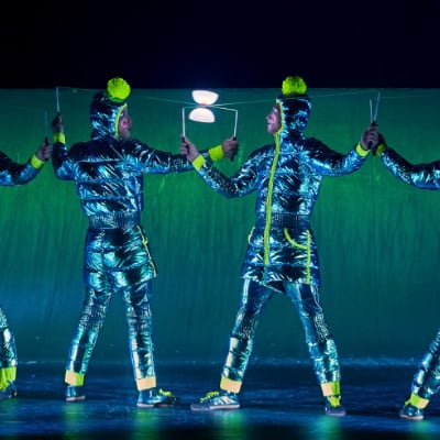 Cuatro artistas vestidos con abrigos aislantes de plumón cromado azul claro realizan diábolo - Twas The Night Before Cirque du Soleil